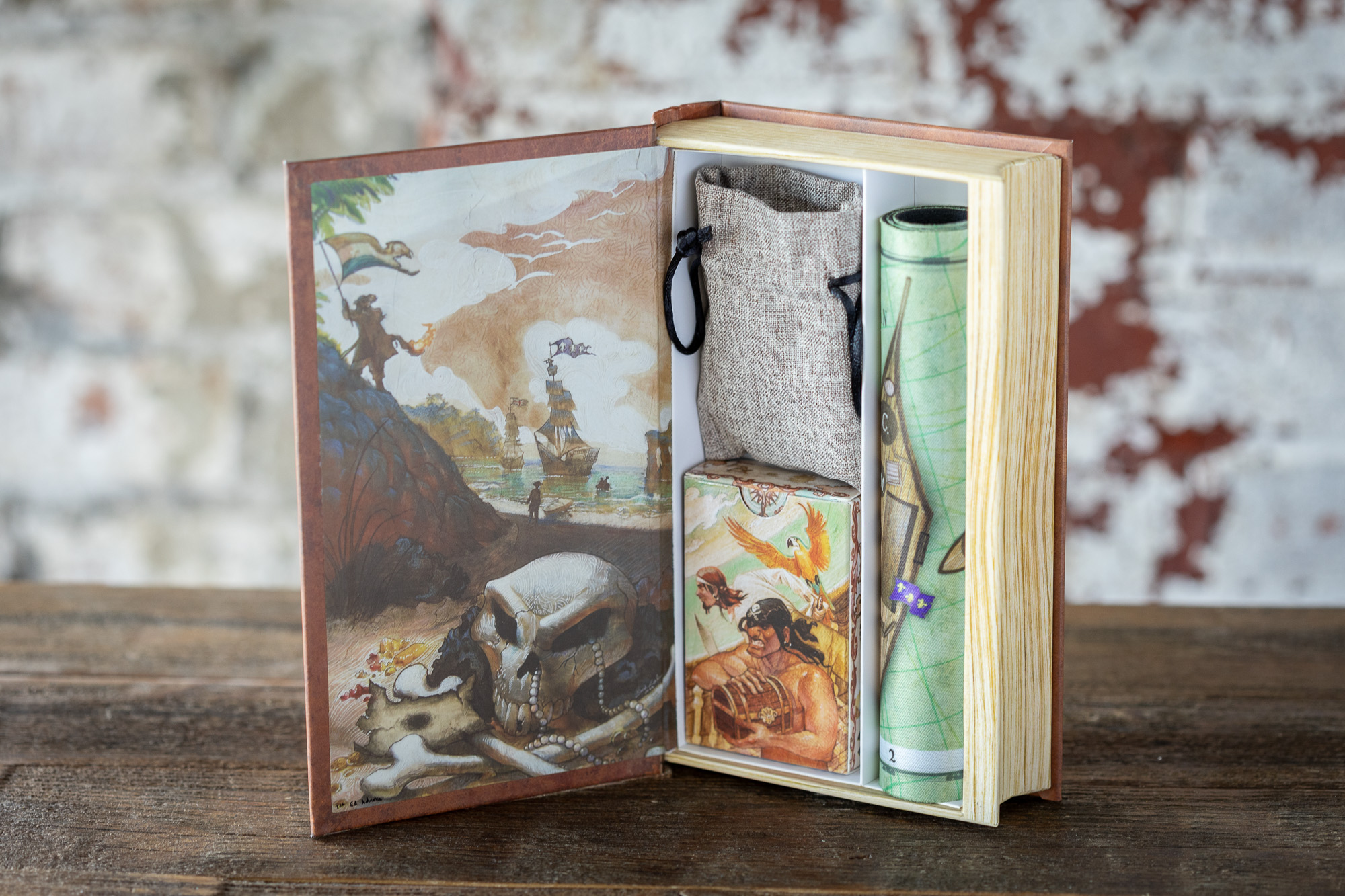 Tortuga 1667 book box open, showing the illustrated inside cover, linen treasure bag, card deck and rolled map
