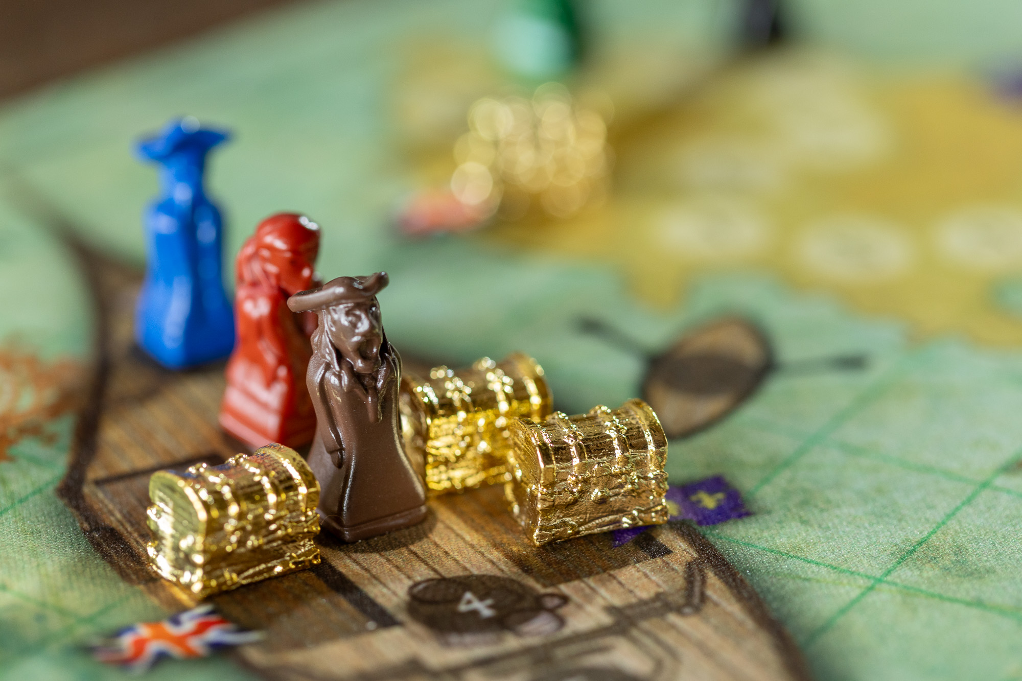 Pirate pawns and gold treasure chests on the deck of a ship on the Tortuga 1667 map
